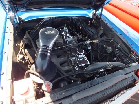 Engine bay of a blue Ford with black cold-air intake and finned valve covers