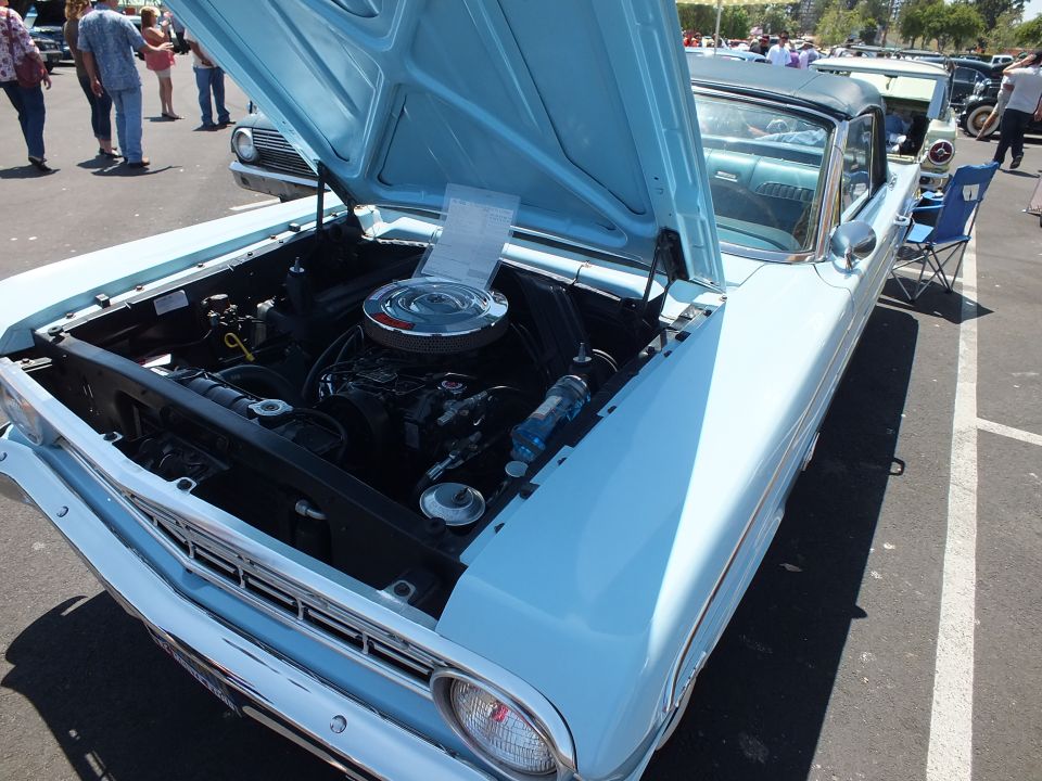 Light blue classic car with hood open at an outdoor car show