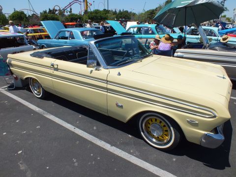Cream-colored classic convertible at an outdoor car show