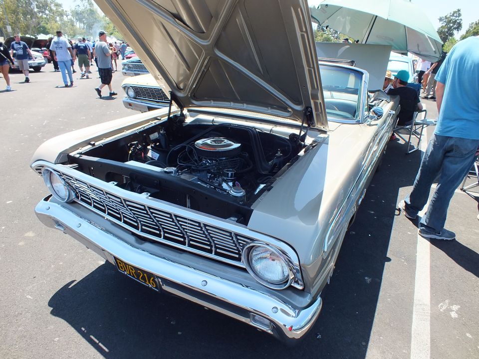 Tan Ford classic with hood up and yellow California plate at a car show