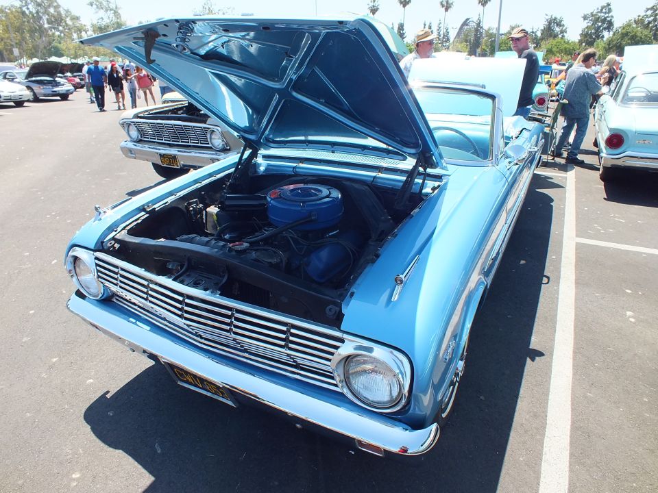 Blue classic Ford with hood open showing engine at a car show