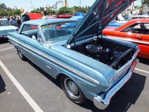 Light blue classic two-door hardtop with hood open at a car show