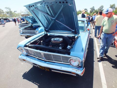 Blue classic Ford with hood up and yellow plate at outdoor car show