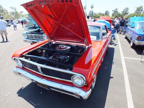 Red classic Ford with hood up showing engine at a car show