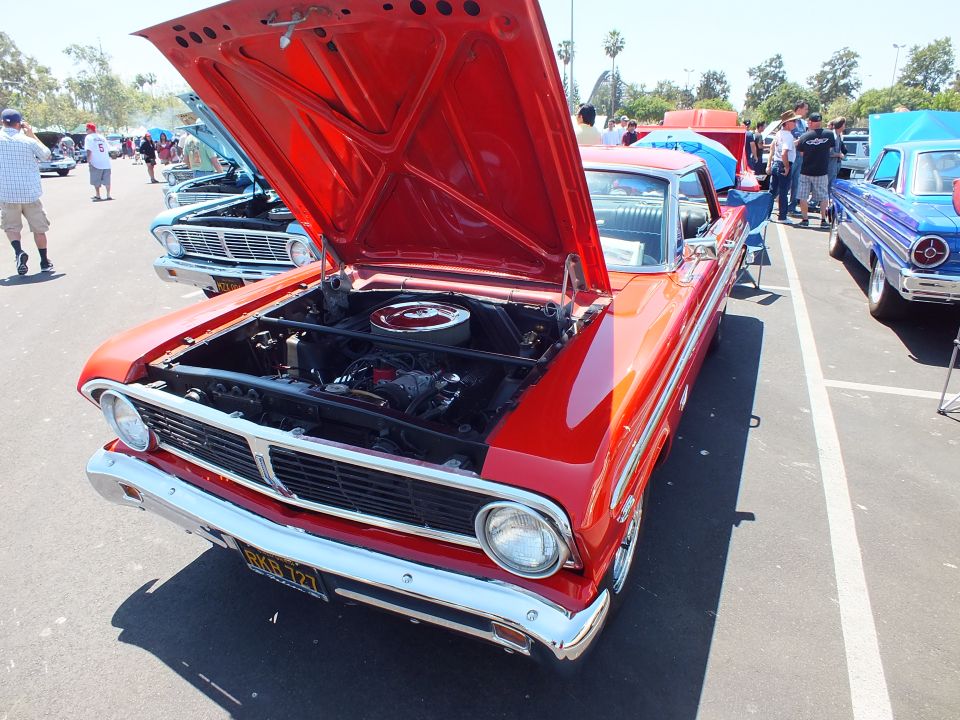 Red classic Ford with hood up showing engine at a car show