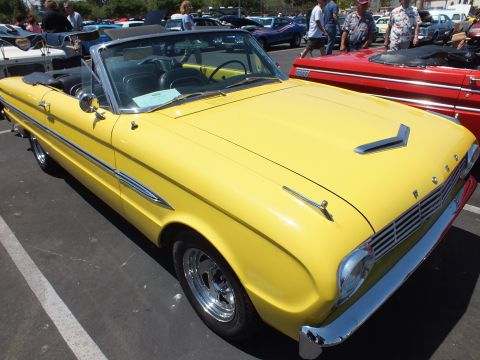 Bright yellow classic convertible with FORD-lettered hood at a car show