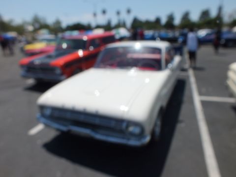 Blurry photo of a white classic car at an outdoor car show