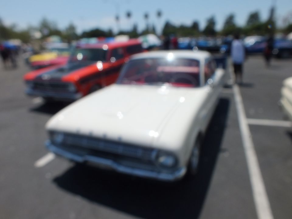 Blurry photo of a white classic car at an outdoor car show
