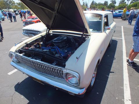 White early-1960s station wagon with hood up showing engine at an outdoor car show