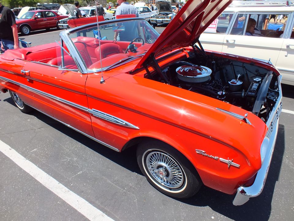 Red convertible with red interior and hood open at a car show