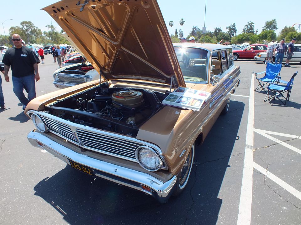 Gold compact station wagon with hood open and display placards at car show