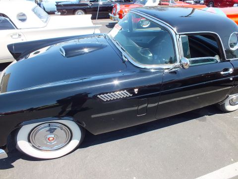 Black two-seat hardtop side profile with porthole window and wide whitewalls
