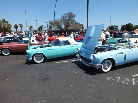 Turquoise and light-blue two-seat classics parked at a busy car show