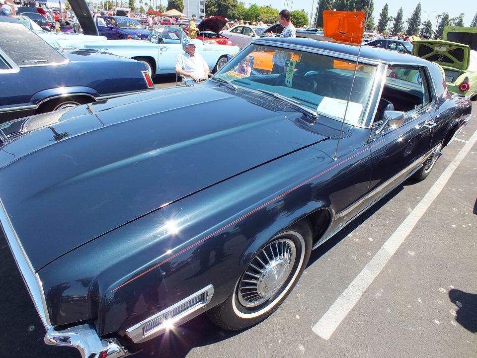 Dark-green late-1960s luxury coupe side profile with wire wheels