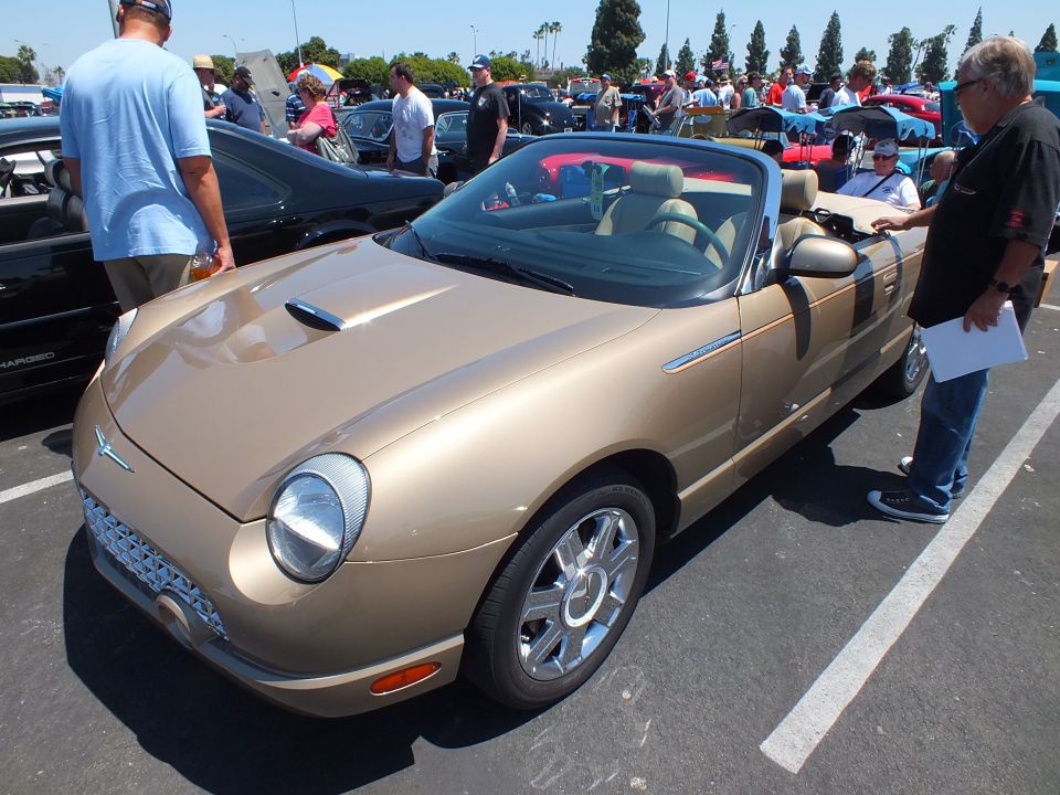Gold Ford Thunderbird convertible with people inspecting it at a show