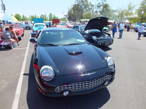 Black retro convertible front view among show cars in a parking lot
