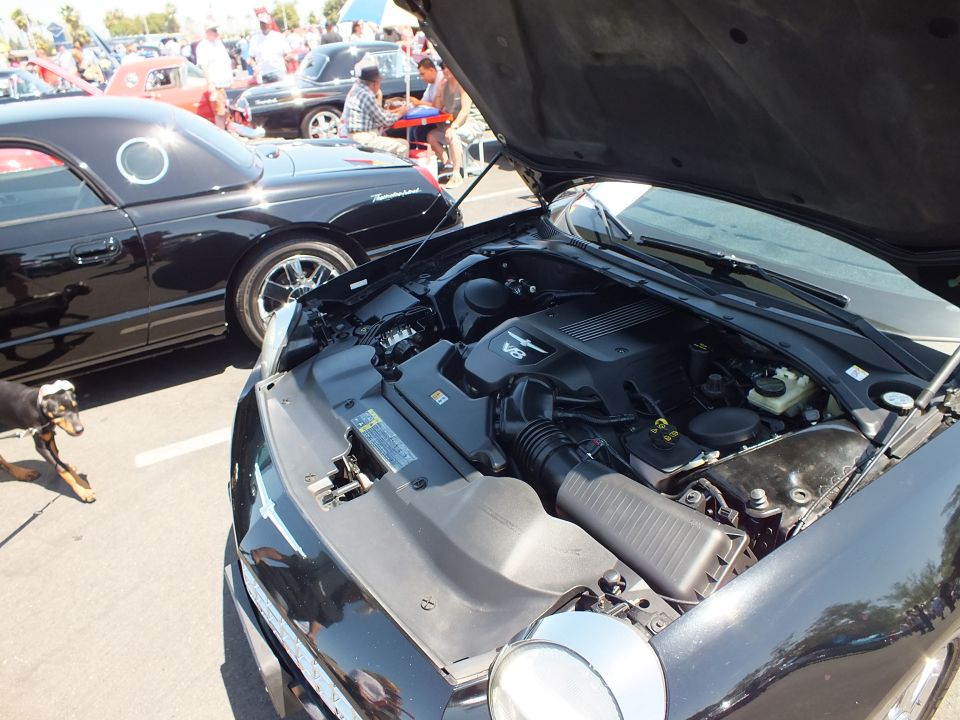 Open engine bay of a black car showing a V8 engine with plastic covers