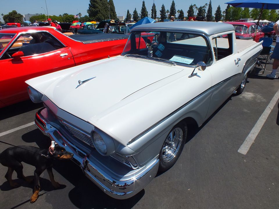 White vintage car-based pickup with dog in foreground at car show