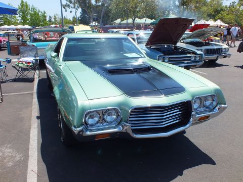 Light green classic car with black hood stripe and open hood at show
