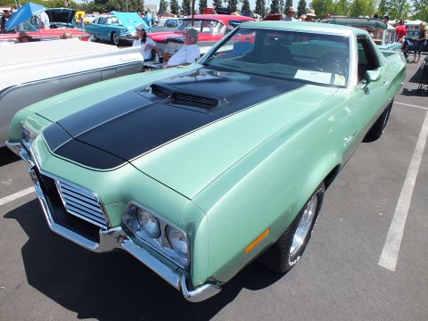 Green Ford Ranchero with black hood stripe in profile at car show