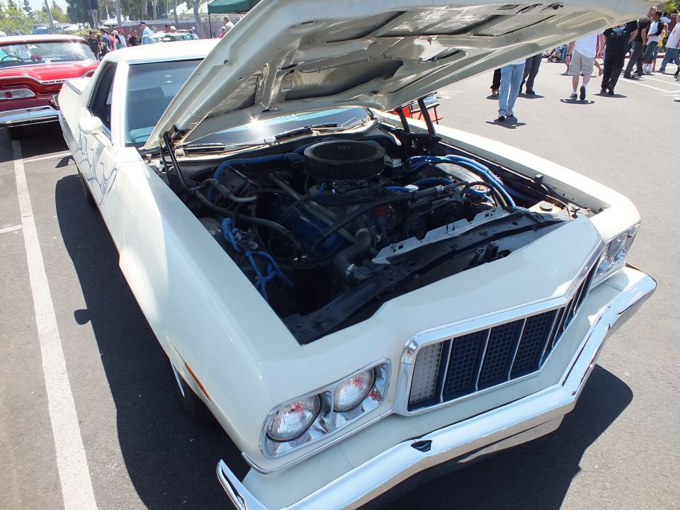White car-based pickup with open hood and blue plug wires on V8