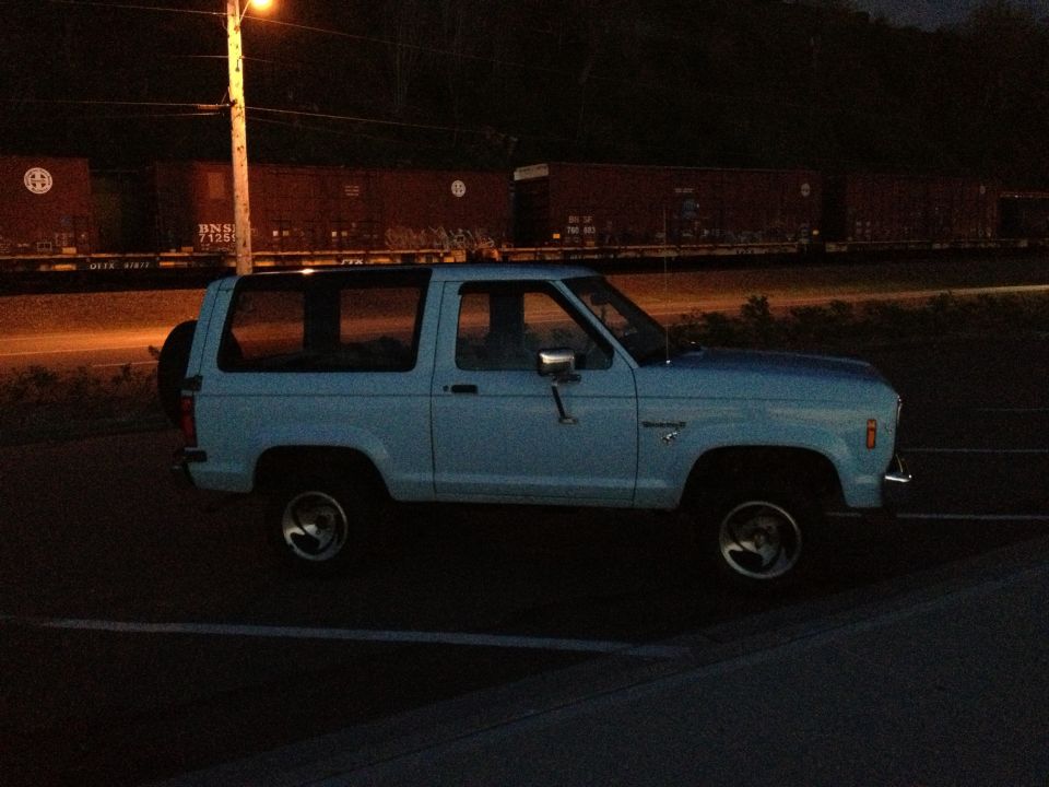 1985 Ford Bronco II parked at night with a train in the background