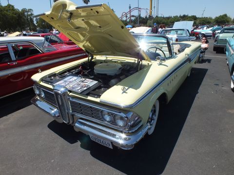 Yellow Edsel convertible with raised hood and chrome grille at a car show