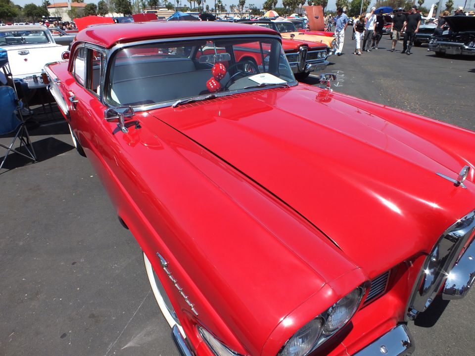 Red 1950s sedan front fender and hood close-up at a car show