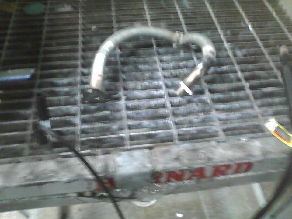 Metal exhaust pipe section on a metal grate, with red lettering visible on the grate's edge