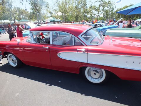 Red and white Edsel four-door sedan side view at a car show