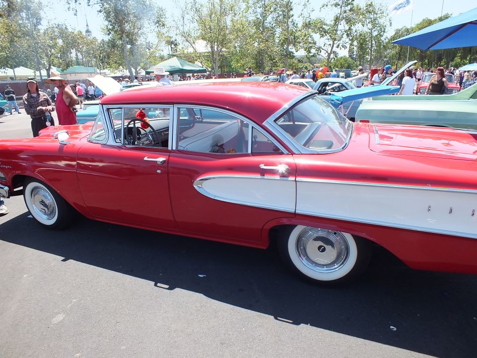 Red and white Edsel four-door sedan side view at a car show