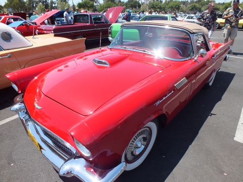 Red Ford Thunderbird with tan top and wire wheels at an outdoor car show