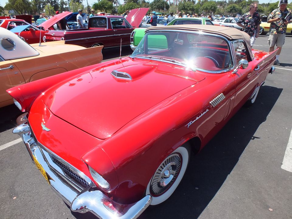 Red Ford Thunderbird with tan top and wire wheels at an outdoor car show