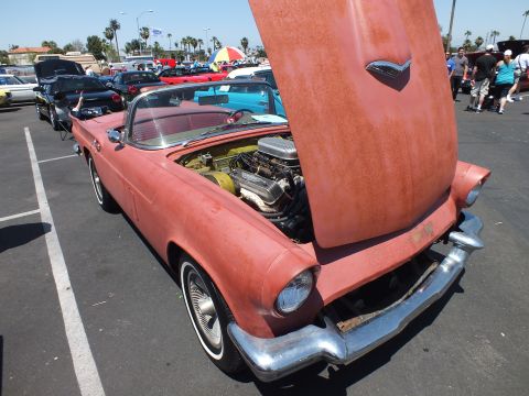 Faded primer-red Ford Thunderbird convertible with hood up at a car show