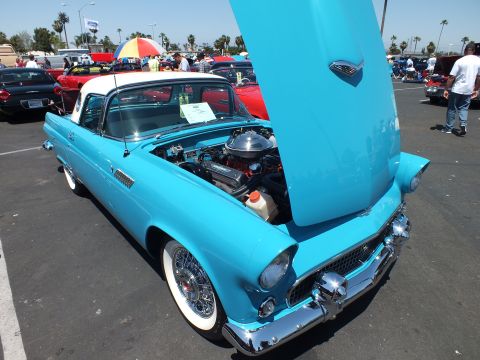 Turquoise Ford Thunderbird with white hardtop and hood up at a car show