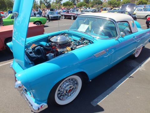 Turquoise Ford Thunderbird with open hood, V8 and wire wheels at a car show