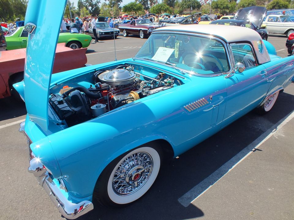 Turquoise Ford Thunderbird with open hood, V8 and wire wheels at a car show