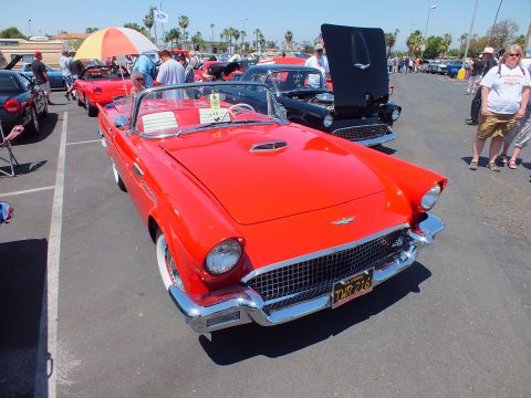 Red Ford Thunderbird convertible with chrome grille at an outdoor car show