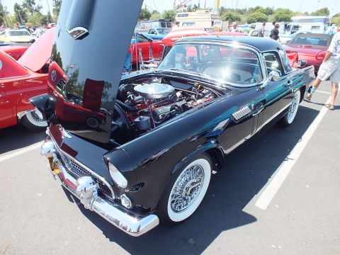 Black Ford Thunderbird hardtop with hood up and wire wheels at show