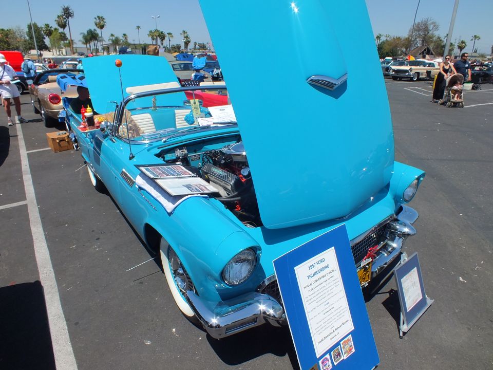Light blue Ford Thunderbird with hood up and display sign at car show