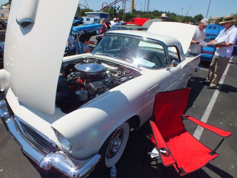 White Ford Thunderbird with hood up and red folding chair at car show
