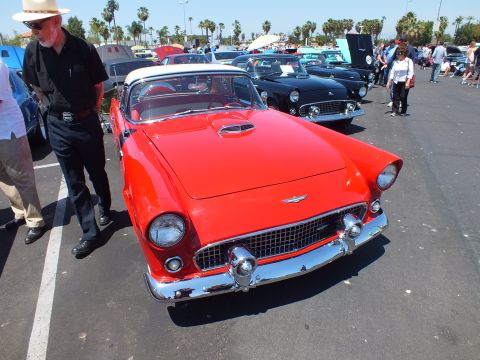 Red Ford Thunderbird with chrome grille and hood scoop at car show