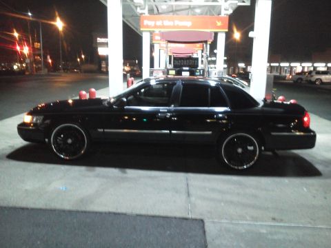 2000 Mercury Grand Marquis - Side view of a black 2000 Mercury Grand Marquis sedan at a gas station, captured at night.