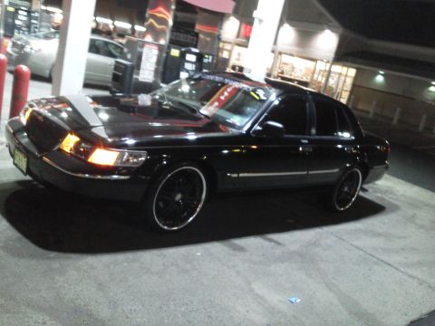 2000 Mercury Grand Marquis - A black 2000 Mercury Grand Marquis is seen from a three-quarter front angle at night.