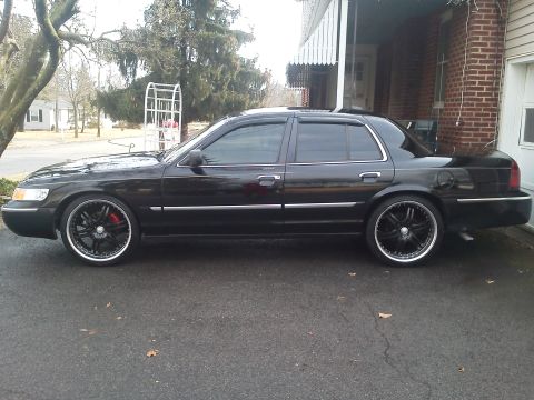 2000 Mercury Grand Marquis - Side view of a black 2000 Mercury Grand Marquis modified with custom rims.