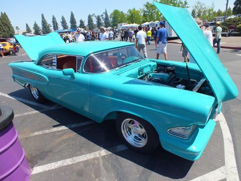 Custom turquoise 1950s coupe with open hood at car show