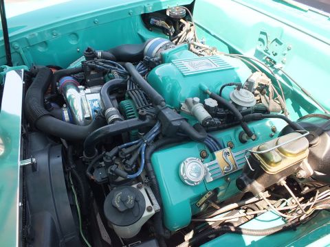 Turquoise engine bay of custom car with supercharger