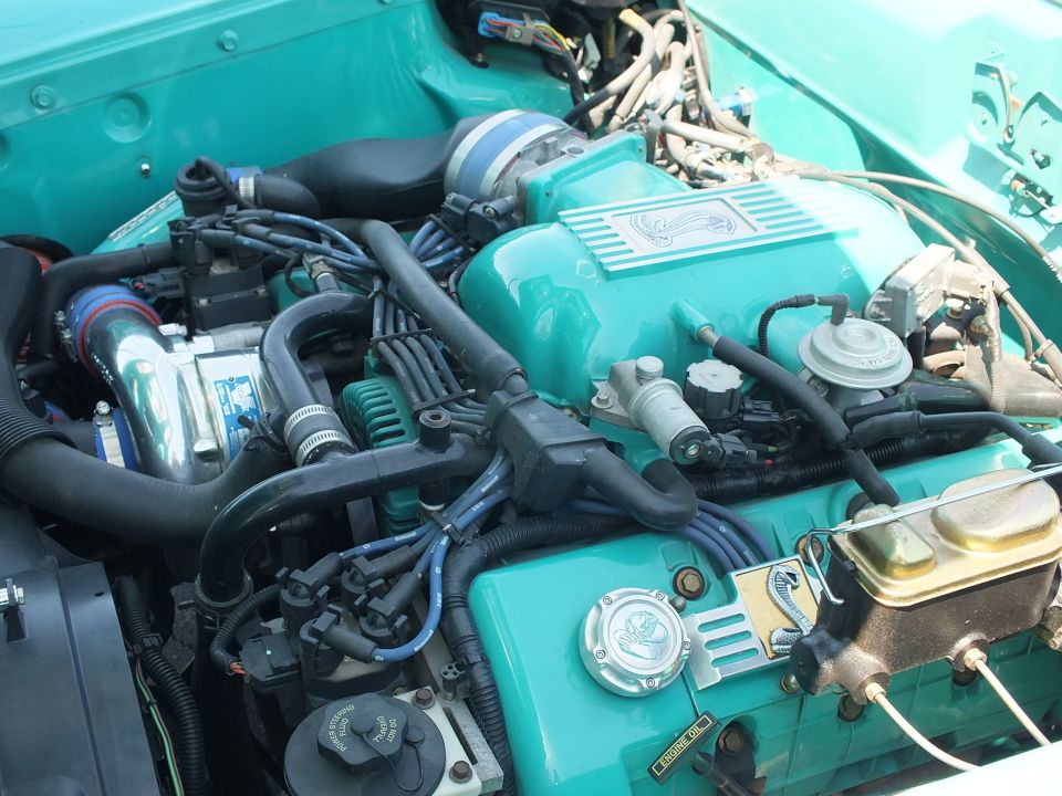 Close-up of turquoise custom engine with supercharger and brake master
