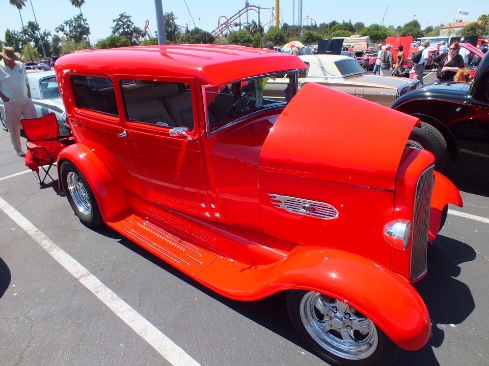 Bright red Model A-style two-door sedan hot rod parked at an outdoor car show