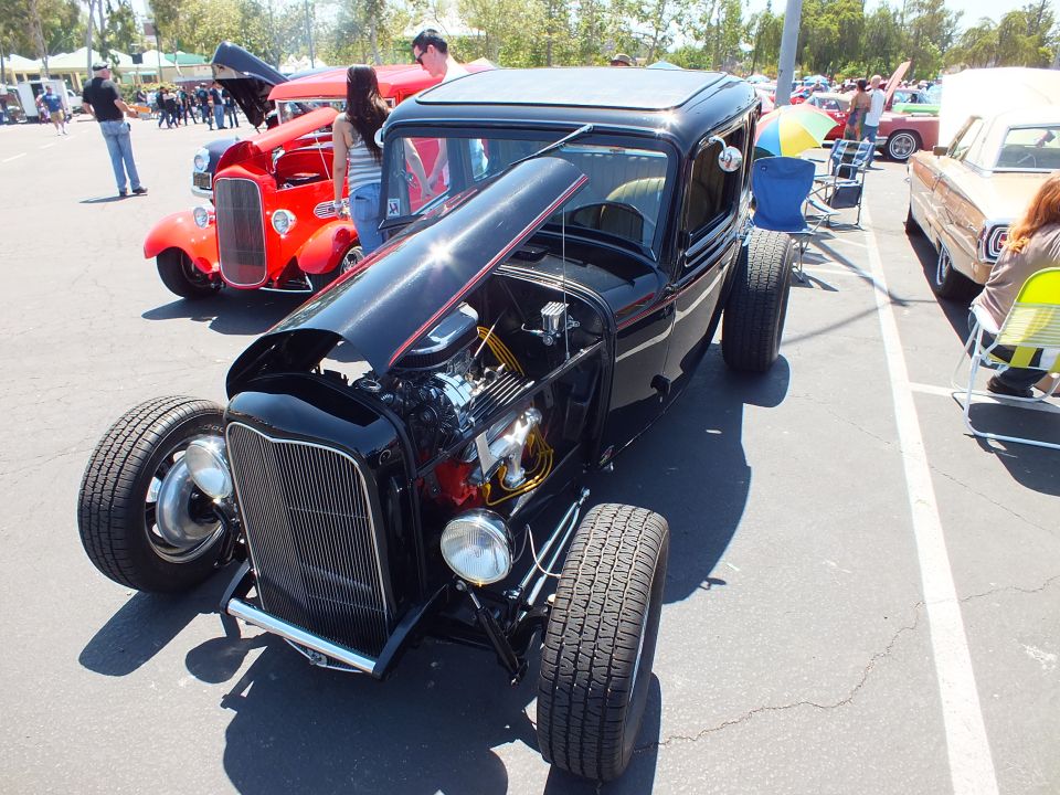 Black 1932-era Ford highboy hot rod with chrome engine and big rear tires at car show